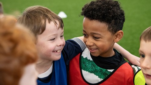 A group of children wearing football bibs on a football pitch