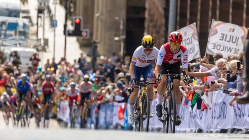 Professional cyclists racing up Montrose Street in Glasgow in front of a cheering crowd during the 2023 UCI Cycling World Championships.