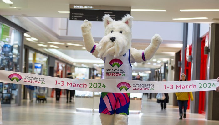 A Scottish Terrier mascot runs through a finish line promoting the 2024 World Athletics Indoor Championships in Glasgow