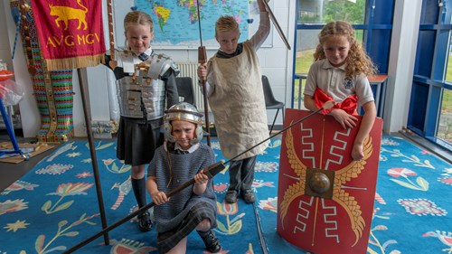 Four children dressed in costumes and holding replica weapons, take part in a Romans workshop at Glasgow Museums Resource Centre