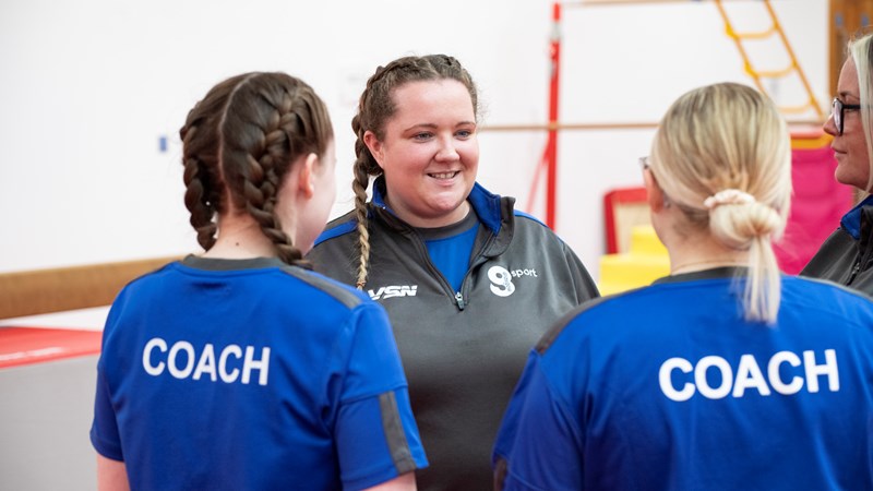 Three gymnastics coaches speaking to each other
