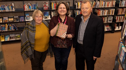 Special Collections Librarian, Susan Taylor at The Mitchell Library holding a copy of Robert Burns: Selected Works, she is standing in the middle of the two authors of the book, Hanna Dyka and Dr Peter Kormylo